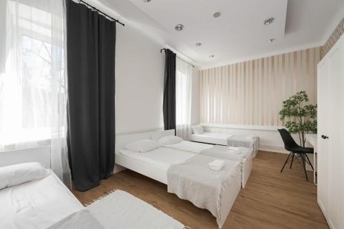 a white bedroom with two beds and a window at ROYAL ROOMS*** in Ljubljana