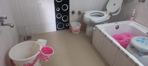 a bathroom with a toilet and a sink and a tub at Raina's Home in Bhuj