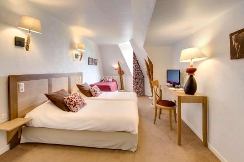 a bedroom with two beds and a desk with a computer at Les Ormes Domaine et Resort in Epiniac