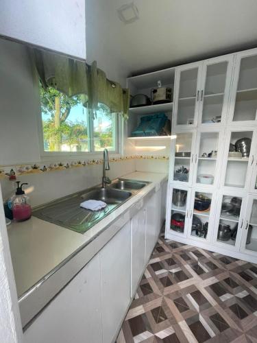 a kitchen with white cabinets and a sink and a window at HUBIBI Villa Staycation Balayan in Sepaco