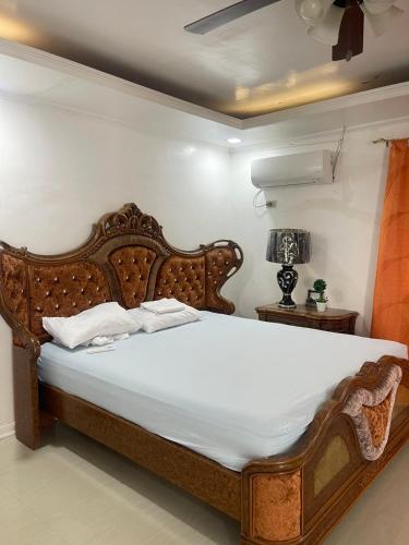 a bedroom with a large wooden bed with white sheets at HUBIBI Villa Staycation Balayan in Sepaco