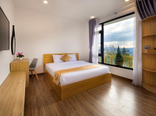 a bedroom with a bed and a large window at ROMANCE HOTEL DALAT in Da Lat