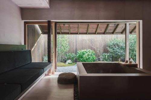a living room with a black couch and a large window at MUDANI 達磨町 Darumacho in Kyoto