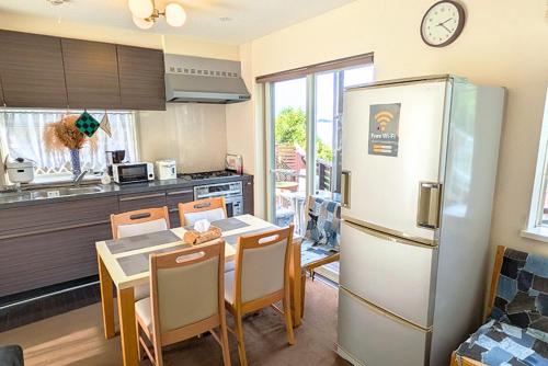 a kitchen with a refrigerator and a table with chairs at 横浜 JS HOUSE Yokohama - ペット犬可 in Yokohama