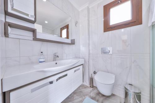a white bathroom with a sink and a toilet at Villa Mars in Kaş