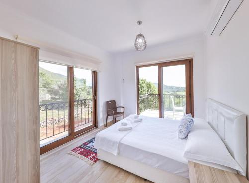 a white bedroom with a bed and a balcony at Villa Mars in Kaş