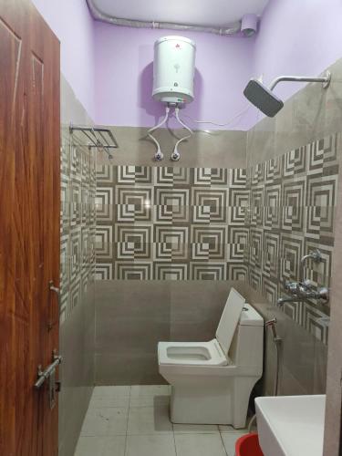 a bathroom with a toilet and a light on the wall at Janki Guest House in New Delhi