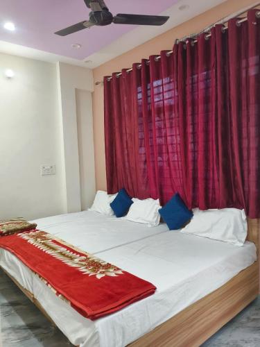 a bedroom with a large bed with red curtains at Janki Guest House in New Delhi