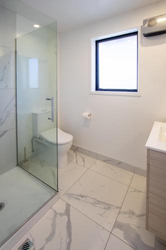 a bathroom with a glass shower and a toilet at Charming 2-Bedroom Apartment - 2 BR, 1 Bath in Christchurch