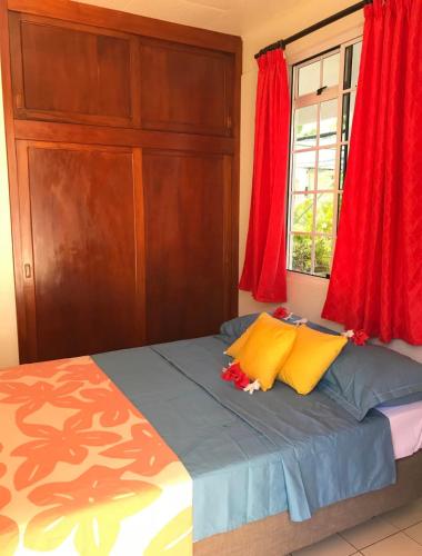 a bedroom with a bed with yellow and red pillows at Mirimiri guest house in Tahu-Naoe