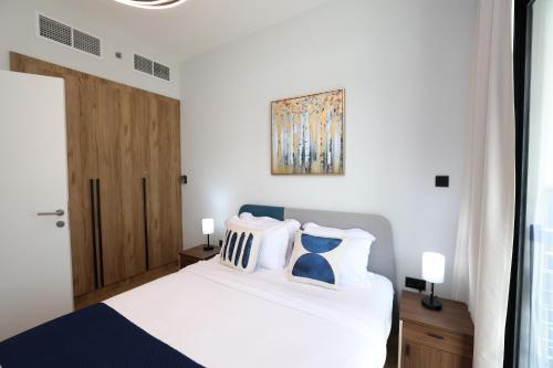 a bedroom with a white bed with blue and white pillows at Maryah Island 1 Bed Junior Next to Cleveland Hospital by Central Stay in Abu Dhabi