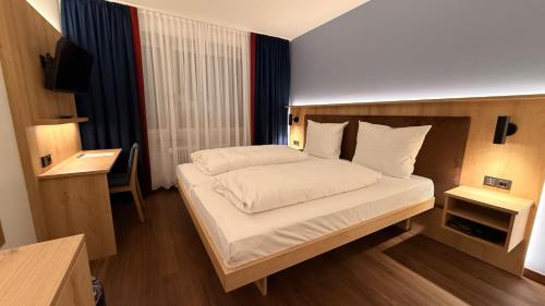 a bedroom with a large bed with white sheets at Hotel Antares München in Munich