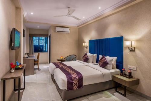a bedroom with a large bed with a blue headboard at Lords Eco Inn Dahej in Dahej