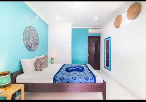 a bedroom with a bed with a blue wall at Isin Gumi Homestay in Amed