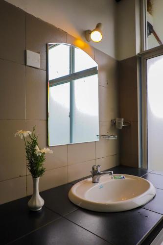 a bathroom with a sink and a window and a vase with flowers at Grosvenor Hotel in Nuwara Eliya