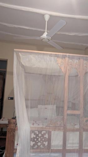 a bedroom with a bed with a ceiling fan at kua garden cottage in Utende
