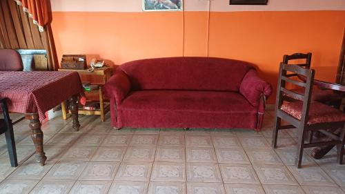 a living room with a red couch and a table at Cliff Club Resort Ooty in Ooty