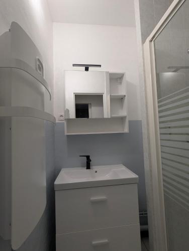 a white bathroom with a sink and a mirror at Appartement montagne in Eaux-Bonnes