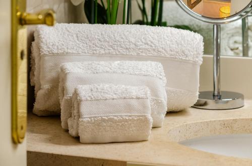 three white towels sitting on a counter next to a sink at Oasis of Aroeira Golf & Beach House in Aroeira