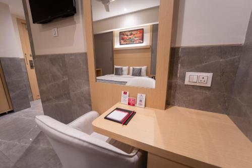 a room with a desk with a mirror and a bed at Shyanu Lords Eco Inn Airoli-Near Mindspace in Navi Mumbai