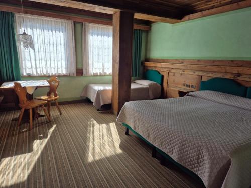 a bedroom with two beds and a table and chairs at Hotel Belvedere wellness in Falcade