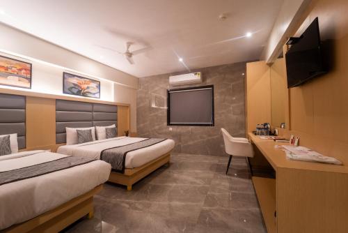 a hotel room with two beds and a flat screen tv at Shyanu Lords Eco Inn Airoli-Near Mindspace in Navi Mumbai