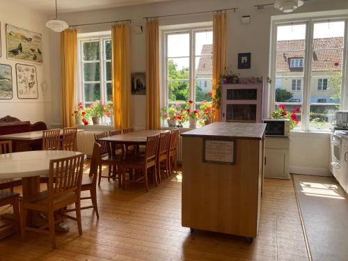 a kitchen and dining room with tables and windows at STF Vandrarhem Backåkra in Löderup