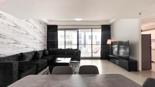 a living room with a black couch and a television at Elegant 2 Bedroom Duplex Apartment Pacific Al Marjan Island in Ras al Khaimah