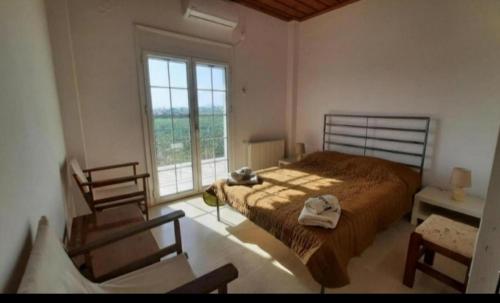 a bedroom with a bed and a large window at MOSXONAS House in Áyioi Asómatoi