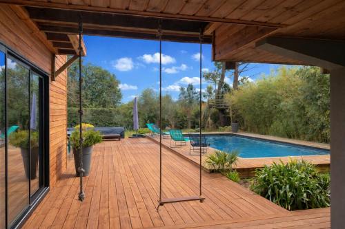 a porch with a swing and a swimming pool at Cap Ferret Villa Océane in Lège-Cap-Ferret