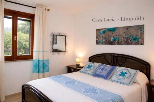 a bedroom with a bed with blue pillows and a window at Casa Lucia vicino al mare in Budoni