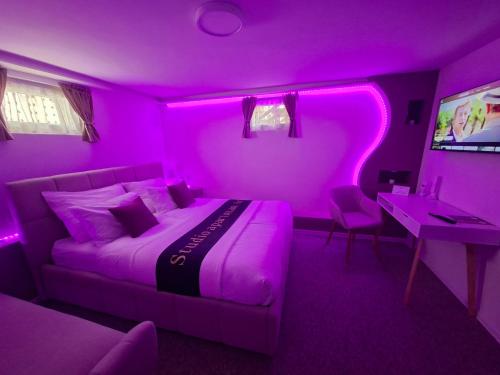 a bedroom with a purple room with a bed and a desk at Studio apartman Aria in Đakovo