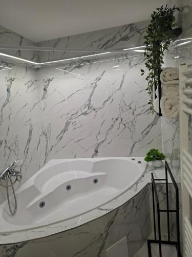 a white bath tub in a bathroom with marble walls at Studio apartman Aria in Đakovo