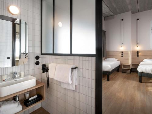 a bathroom with a sink and two beds at ibis Styles Namur in Namur