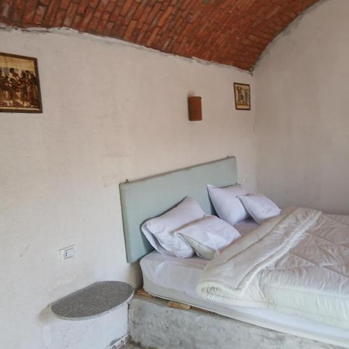 a bed in a room with white sheets and pillows at Asilah kato nubian guest house in Aswan