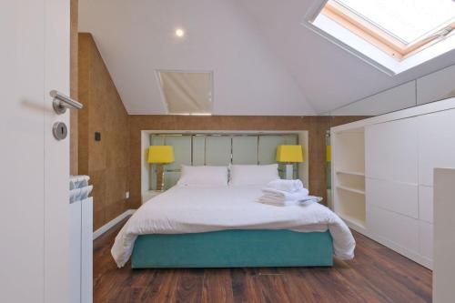 a bedroom with a bed with white sheets and a skylight at Luxury Duplex in Benfica 15 Min to Airport in Lisbon