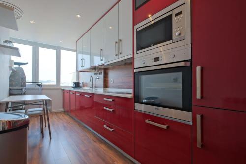 a kitchen with red cabinets and a microwave at Luxury Duplex in Benfica 15 Min to Airport in Lisbon