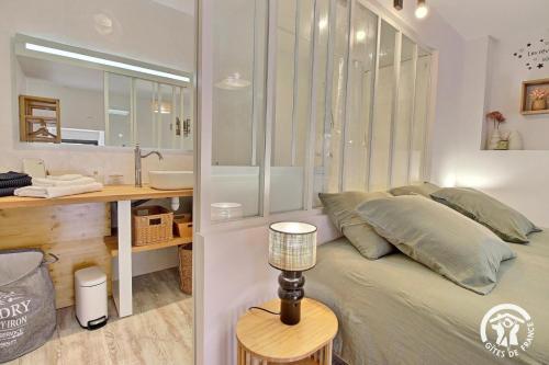 a bedroom with a bed and a bathroom with a sink at Les maisons de l'if - le cottage in Pluméliau
