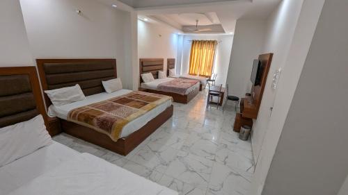 a hotel room with two beds and a television at Hotel Kaushik Palace in Haridwār