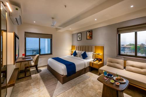 a hotel room with a bed and a desk and a couch at Lords Studio Inn, Jamnagar in Jamnagar