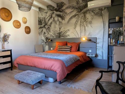 a bedroom with a bed with orange pillows and palm wallpaper at 16 Bis-Gîte-Hôtel-Appartement in Marssac-sur-Tarn