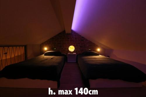 two beds in a room with a purple light at Chez Martine & Pierre in Baillonville