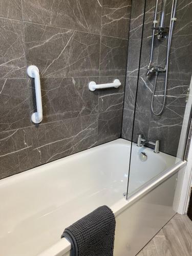a bathroom with a shower with a tub and a sink at Baron Apartment B in Ballymena