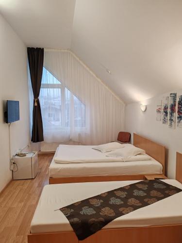 two beds in a room with a window at PENSIUNEA HORA in Braşov