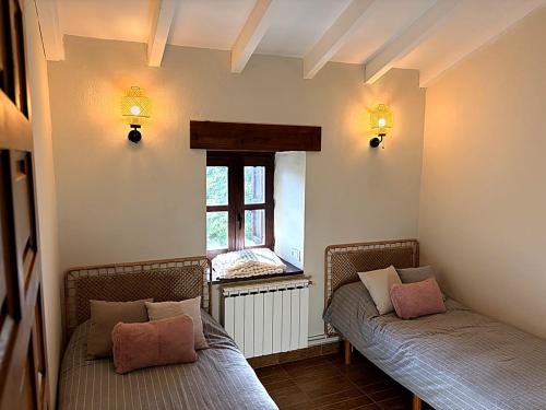 two wicker beds in a room with a window at El Refugio de Redo - balcón a los Picos de Europa in Camaleño