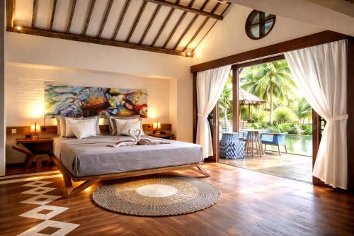 a bedroom with a bed with a painting on the wall at The White Key Luxury Villas in Gili Trawangan