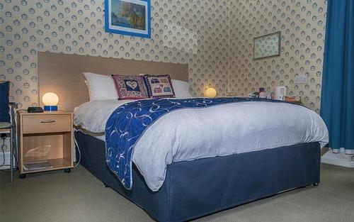 a bedroom with a large bed with a blue comforter at Hamilton House Guest House in Oban