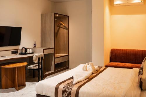 a hotel room with a bed and a desk with a computer at The Hue House in Sibsāgar