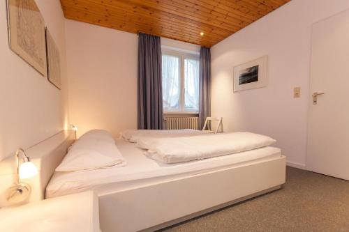 a bedroom with a large white bed with a window at Bungalow-Finlandia in Westerland