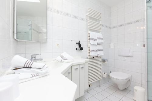 a white bathroom with a sink and a toilet at Bungalow-Finlandia in Westerland